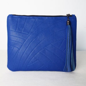 May include: A bright blue clutch bag with a stitched geometric design. It has a black zip and a matching blue tassel. This accessory is ideal for carrying essentials, a fashionable item.