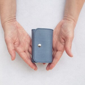 May include: A small, light blue leather key holder with a silver button closure.