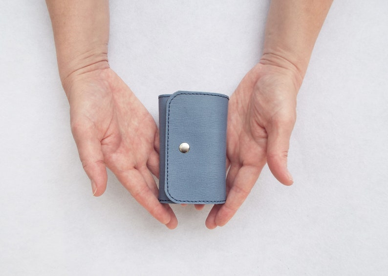 May include: A small, light blue leather key holder with a silver button closure.