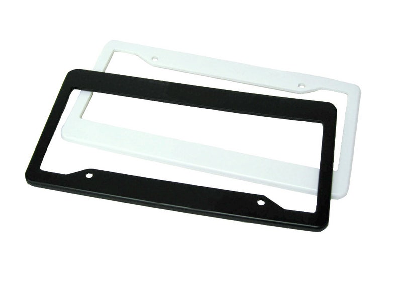 Pode incluir: Duas molduras retangulares para placas de carro, uma preta e outra branca, est&atilde;o sobrepostas. As molduras t&ecirc;m cantos arredondados e orif&iacute;cios pr&eacute;-perfurados para montagem. A moldura branca est&aacute; ligeiramente atr&aacute;s da preta.
