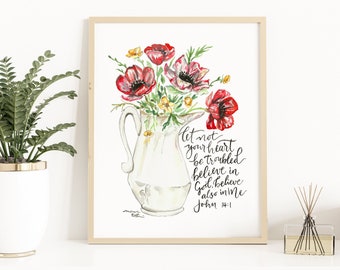 May include: Watercolor floral art print featuring red poppies in a white pitcher. The artwork includes the script "Let not your heart be troubled, believe in God, believe also in Me, John 14:1." The print is in a light wood frame.