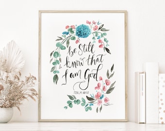 May include: A framed watercolor print with a floral wreath surrounding the text "Be still and know that I am God" with the scripture reference "Psalm 46:10".