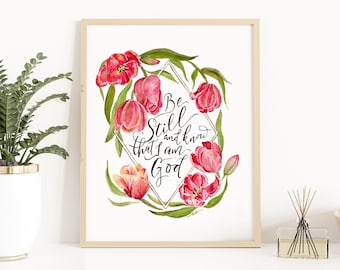 May include: A framed watercolor print with a white background and pink tulips surrounding a diamond-shaped frame with the text "Be Still and know that I am God".