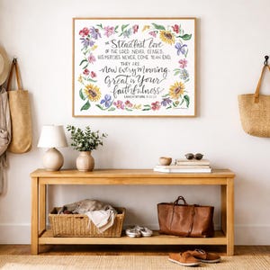 Puede incluir: Una impresi&oacute;n floral enmarcada con el texto "El amor constante del Se&ntilde;or nunca cesa". Una consola de madera exhibe una l&aacute;mpara, un jarr&oacute;n, libros y una bolsa de cuero. Una bolsa de paja y un sombrero cuelgan de la pared.