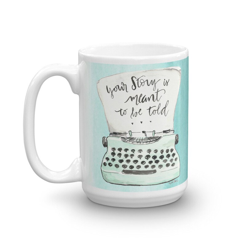 May include: White ceramic mug with a blue and green illustration of a typewriter with the text "Your story is meant to be told".