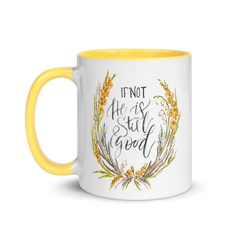 May include: White ceramic mug with a yellow handle and interior. The mug features the text "IF NOT He is Still good" in a handwritten style, surrounded by a floral wreath design with yellow and green accents.