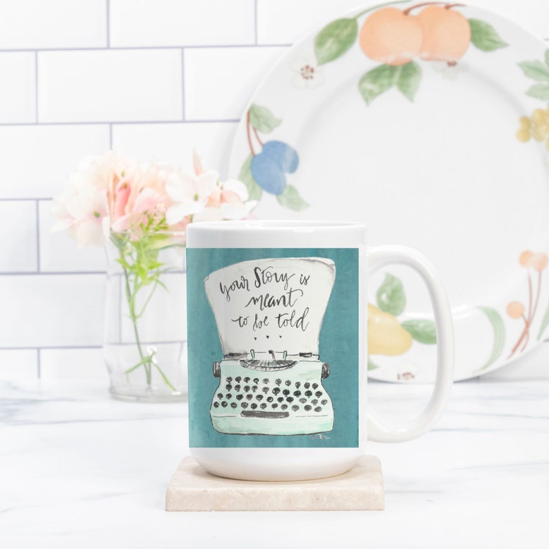 May include: White ceramic mug with a teal blue background featuring a vintage typewriter with the text "Your story is meant to be told".