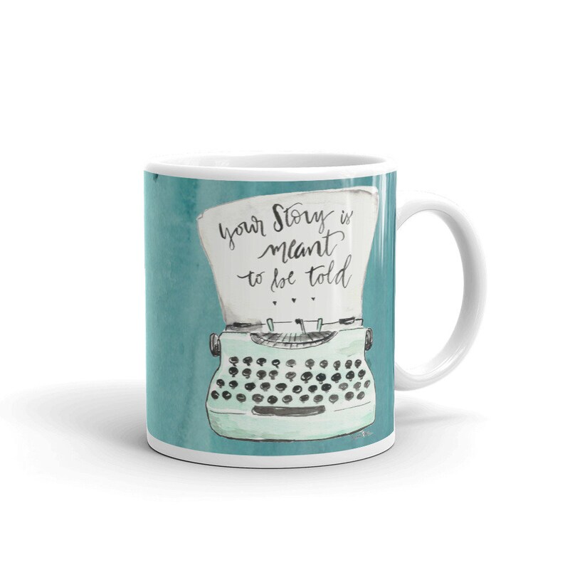 May include: White ceramic mug with a teal blue background featuring a vintage typewriter with a sheet of paper that reads "Your story is meant to be told".