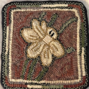 May include: A hand-stitched rug with a floral design. The rug is made of wool and has a brown, green, and white color scheme.