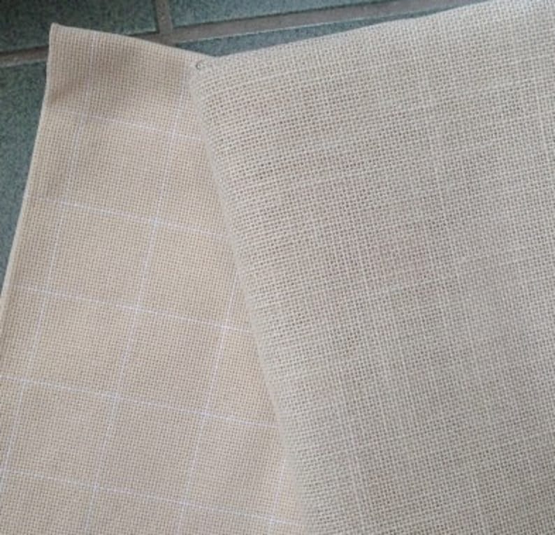 May include: Two pieces of beige fabric, one with a grid pattern and the other with a smooth texture.