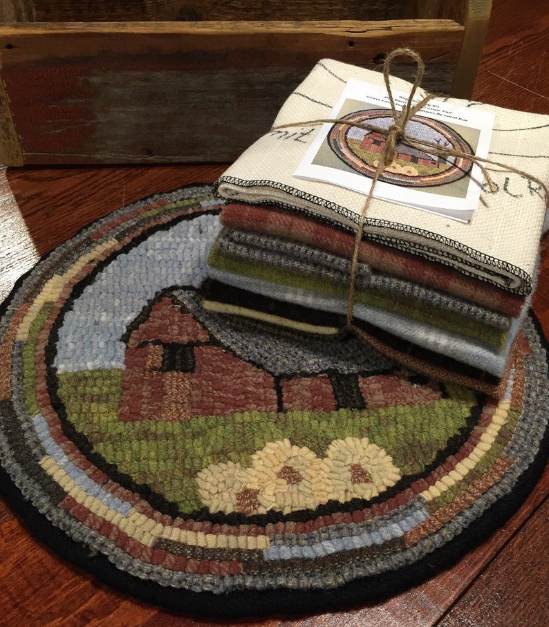 May include: A round, hand-stitched rug with a barn scene, featuring a red barn, green grass, and a blue sky. A stack of fabric squares and a matching printed design are tied together with twine. The rug's border has a variety of colors.