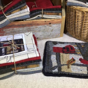 May include: A set of wool fabric squares in various colors and patterns, including red, white, and blue, bundled together with twine. The fabric squares are arranged in a stack and are ready for a craft project. A finished wool rug with a red cardinal bird design is also shown.