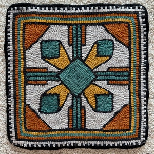 May include: A square rug with a geometric design in shades of teal, yellow, orange, and black on a white background.
