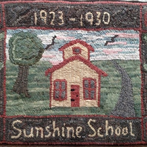 Puede incluir: Una alfombra vintage que representa una escuela de una sola planta con un techo rojo y un letrero que dice "Sunshine School". La alfombra tiene un borde marr&oacute;n con acentos rojos y los a&ntilde;os "1923-1930" est&aacute;n cosidos en la parte superior central.