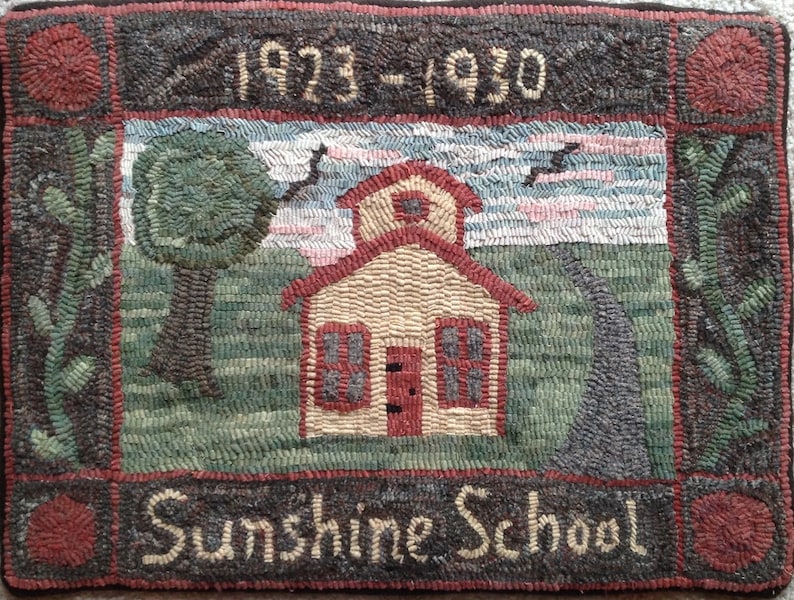 Puede incluir: Una alfombra vintage que representa una escuela de una sola planta con un techo rojo y un letrero que dice "Sunshine School". La alfombra tiene un borde marr&oacute;n con acentos rojos y los a&ntilde;os "1923-1930" est&aacute;n cosidos en la parte superior central.