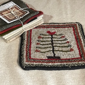May include: A hand-hooked wool rug with a red bird on a green tree with red berries. The rug has a black, red, and white border. The rug is on a beige surface. "Home Tree Mat 12" x 12" Project Kit & Card Art"
