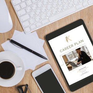 Może przedstawiać: Tablet cyfrowy wyświetlający dokument planu kariery z złotym logo K i tekstem "CAREER PLAN". Dokument zawiera zdjęcie osoby pracującej na laptopie. Tablet znajduje się na drewnianej powierzchni z filiżanką kawy, długopisem, białą myszką, klawiaturą i smartfonem.