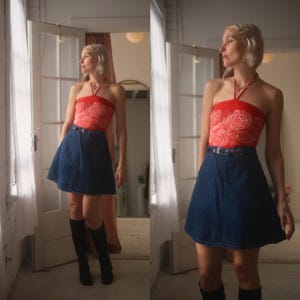 May include: A red halter top featuring a white rose pattern paired with a dark blue denim skirt. The skirt has a high waist with a thin belt and a flared silhouette. The outfit is completed with black knee-high boots.