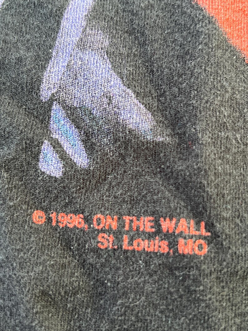 May include: Black t-shirt with red text that reads "&copy; 1996, ON THE WALL St. Louis, MO".