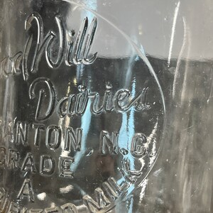 May include: A vintage glass milk bottle with the text "Good Will Dairies, Canton, N.C. Grade A" embossed on the side.