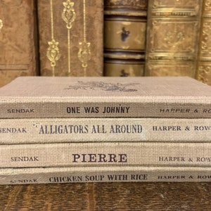 May include: A stack of four children's books with brown covers. The titles are "One Was Johnny", "Alligators All Around", "Pierre", and "Chicken Soup With Rice". All books are by Maurice Sendak and published by Harper & Row.