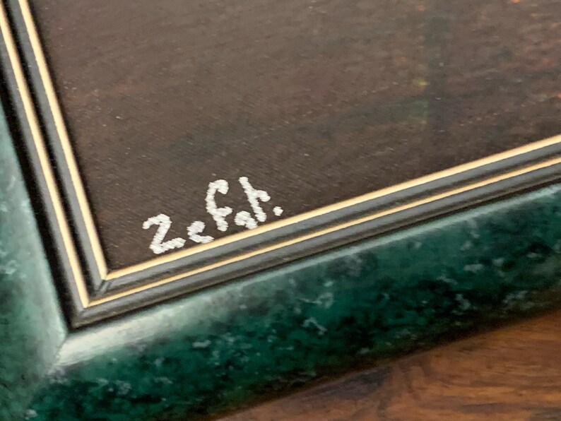 Puede incluir: Primer plano de un marco verde con un borde dorado. La firma "Z. Fah." est&aacute; escrita en pintura blanca sobre la superficie marr&oacute;n del marco.