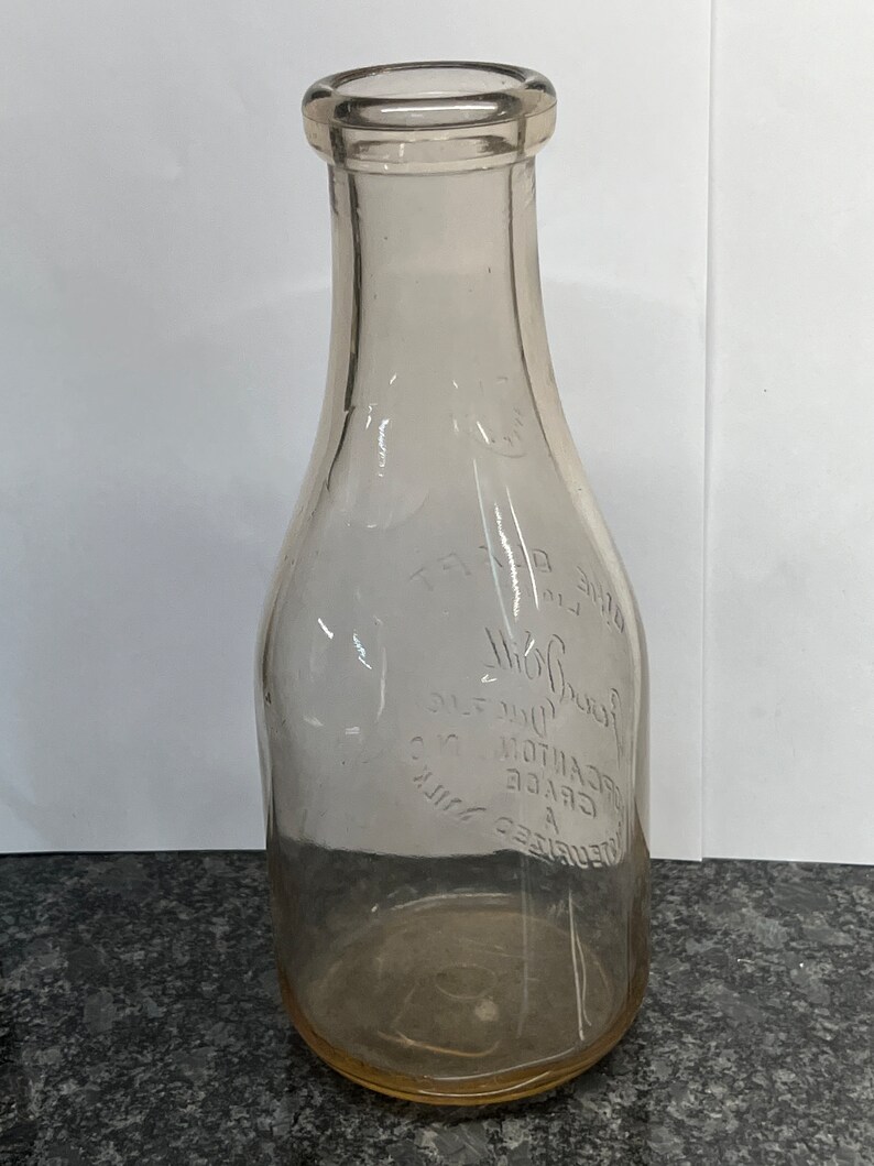 May include: A clear glass milk bottle with a textured surface. The bottle has the text "REFRIGERATED MILK GRADE A DECANTON CO. JERSEY DAIRY" embossed on the side.