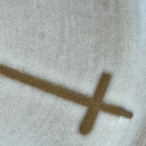 May include: A white ceramic plate with a brown cross design.