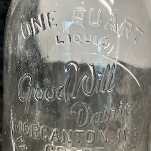 May include: A clear glass milk bottle with the text "One Quart Liquid Good Will Dairies Morgantown, NC Pasteurized Grade A Milk" embossed on the side.
