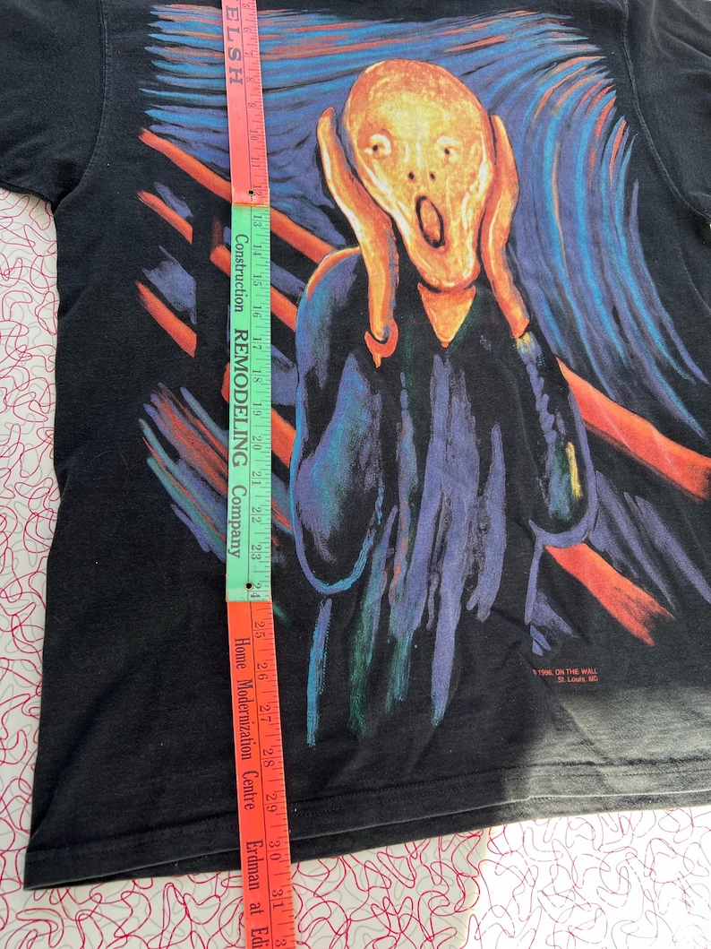 May include: Black t-shirt with a colorful graphic print of Edvard Munch's "The Scream". The print features a person with their hands over their ears, a bright yellow face, and a wide-open mouth. The background is a swirling mix of blue, green, and orange.