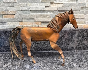 May include: A handcrafted metal horse sculpture in shades of copper and bronze. The horse has a detailed mane and tail, with a textured body. The sculpture is posed in a standing position, showcasing its elegant form.