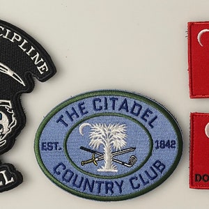 May include: Four embroidered patches, two black and white, one blue and green, and two red with white and black details. The black and white patches feature a skull and crossbones with the text "Lords of Discipline" and "Citadel". The blue and green patch features a white palmetto tree with the text "The Citadel Country Club Est. 1842". The red patches feature a palmetto tree and a rattlesnake with the text "Don't Tread On Me".