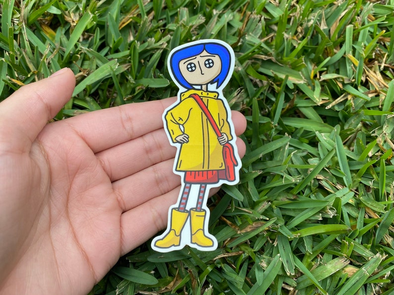 May include: A sticker featuring a cartoon character with blue hair, button eyes, and a yellow raincoat. The character is holding a red bag and wearing a red skirt, striped socks, and yellow boots. The sticker is on a white background.