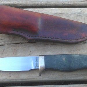 May include: A small, stainless steel knife with a dark green handle and a leather sheath. The knife has the words "Bear Creek" engraved on the blade.