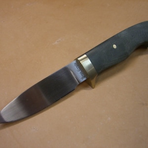 May include: A hunting knife with a black handle, brass bolster and a stainless steel blade. The blade has the text "Buck 119 Special" etched into it.