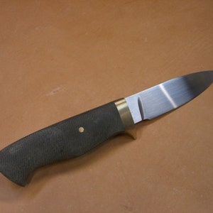May include: A knife with a black handle, brass bolster and a stainless steel blade.