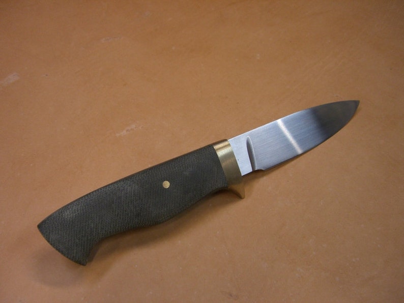 May include: A knife with a black handle, brass bolster and a stainless steel blade.