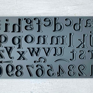 May include: Gray silicone mold with uppercase letters and numbers for baking or crafting. The mold includes the alphabet from A to Z and numbers 0 to 9.