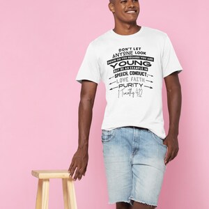 Peut inclure: T-shirt blanc avec texte noir : « DON'T LET ANYONE LOOK DOWN ON YOU BECAUSE YOU ARE YOUNG » et d'autres mots inspirants. La personne porte un short en jean bleu. Un petit tabouret en bois est à côté de la personne.