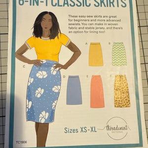 May include: A sewing pattern for 6-in-1 classic skirts. The pattern features a woman wearing a yellow shirt and a blue skirt with white floral designs. The pattern includes skirt styles A, B, C, D, E, and F. Sizes XS-XL.