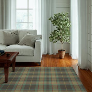 May include: A living room with a white sofa, a wooden coffee table, a potted plant, and a plaid rug. The rug has a green, brown, and yellow tartan pattern.