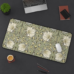 Op de afbeelding: Een rechthoekige bureaumuispad met een bloemenpatroon van crèmekleurige irissen, groene bladeren en kleine gele bloemen op een donkere achtergrond. De pad heeft een zwarte rand. Een witte muis ligt erop.