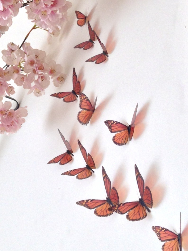 May include: A set of 10 orange and black butterfly wall decals. The butterflies are arranged in a diagonal line, with the largest butterfly at the bottom.