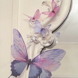 May include: A white ornate frame with three pink butterflies and a larger purple and blue butterfly with glitter accents.