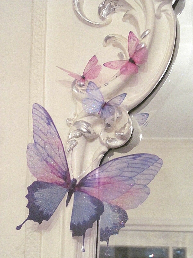 May include: A white ornate frame with three pink butterflies and a larger purple and blue butterfly with glitter accents.