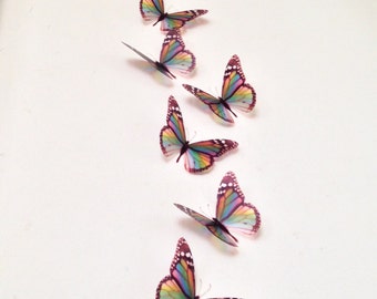 May include: A row of colorful butterfly wall decor with iridescent wings. The butterflies are arranged in a vertical line, with the largest butterfly at the bottom and the smallest butterfly at the top.
