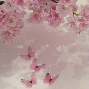 May include: Pink cherry blossoms with delicate petals hang from a branch, creating a soft, romantic backdrop for five pink butterfly decorations.