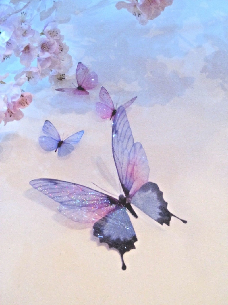 May include: Four delicate butterflies with iridescent wings in shades of purple and blue are arranged on a white background. The butterflies are arranged in a cluster, with the largest butterfly in the center.
