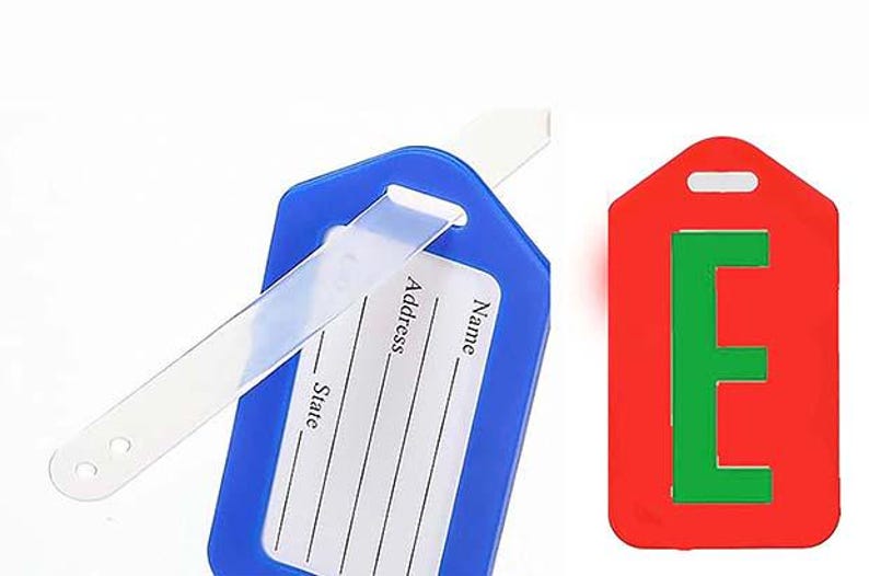 May include: Two luggage tags. One is blue with a clear strap and a white insert for name, address, and state. The other is red with a green letter "E".