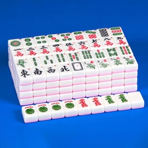 May include: A set of white Mahjong tiles arranged in a rectangular block with a single row of tiles placed in front. Each tile features distinct red, green, and black engraved symbols, including Chinese characters, floral designs, and Joker labels.